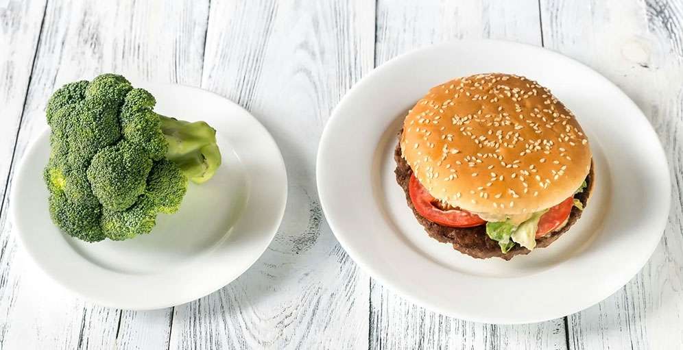 Hamburger and broccoli on separate plates representing food choices and mood