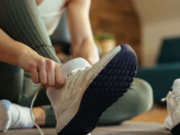 Person putting on running shoes to build a healthy daily habit