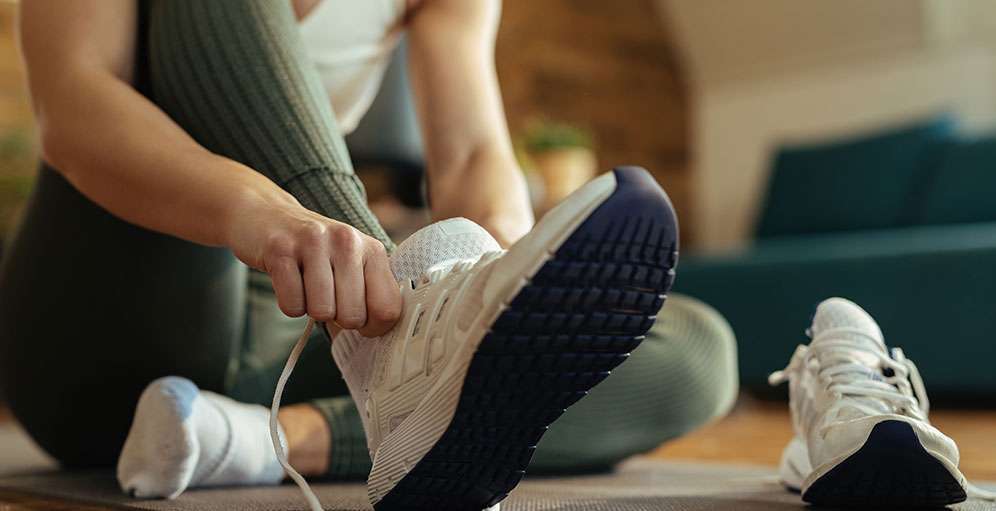 Person putting on running shoes to build a healthy daily habit