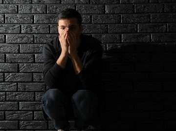 Man in despair leaning against wall.